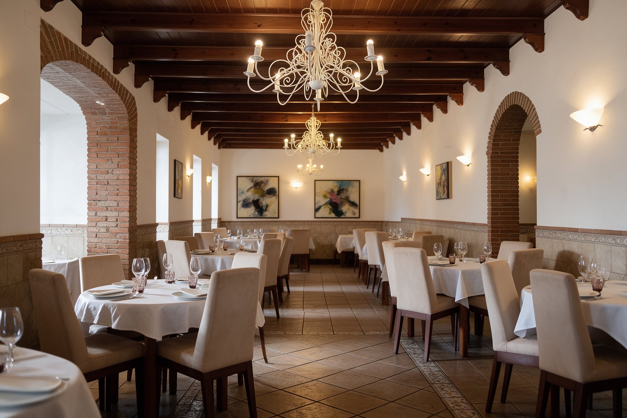 Interior de La Taberna de Flores con vigas de madera, lamparas y mesas vestidas de blanco