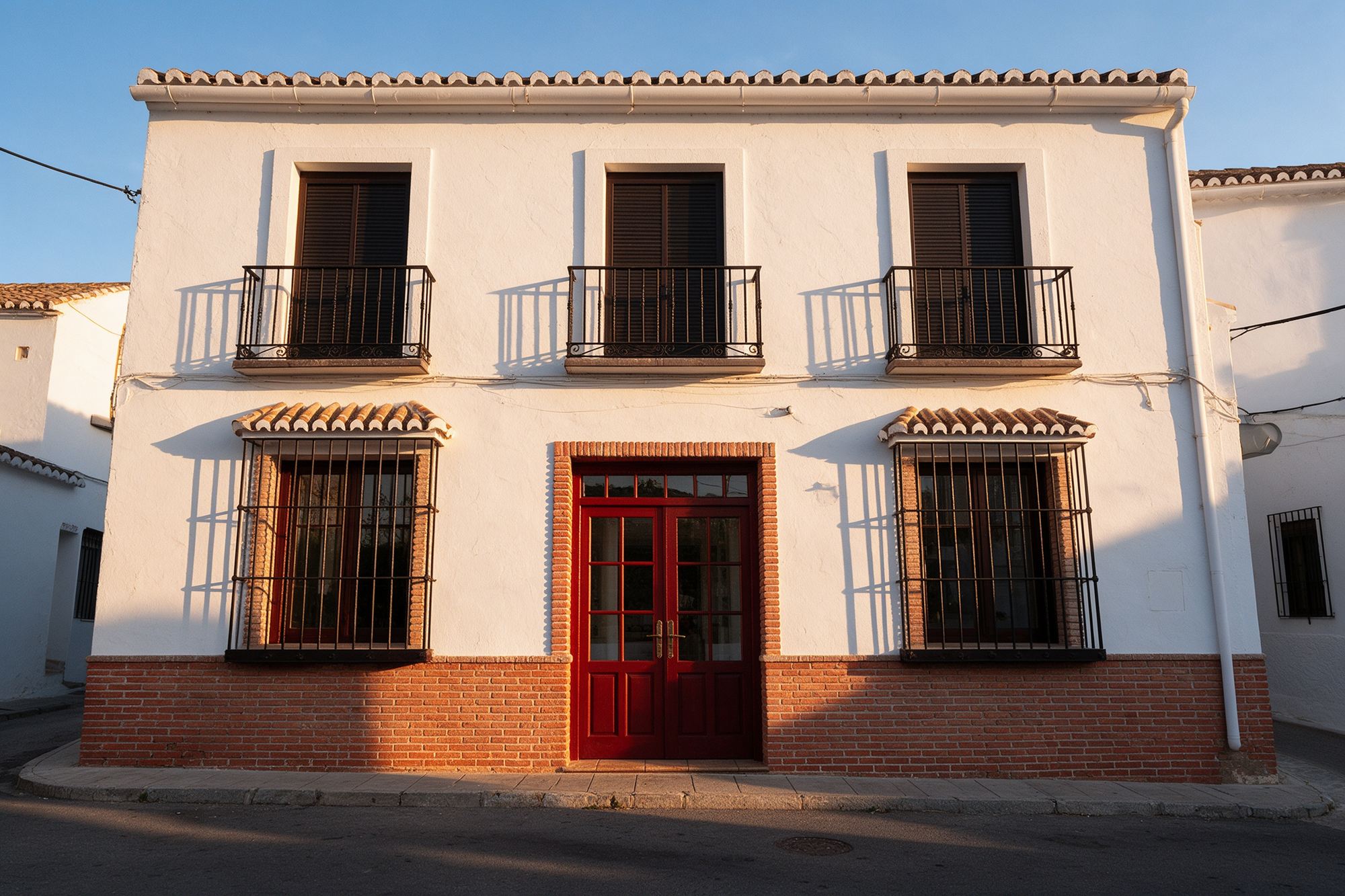 Fachada blanca de dos plantas de la taberna en el pueblo de Colmenar